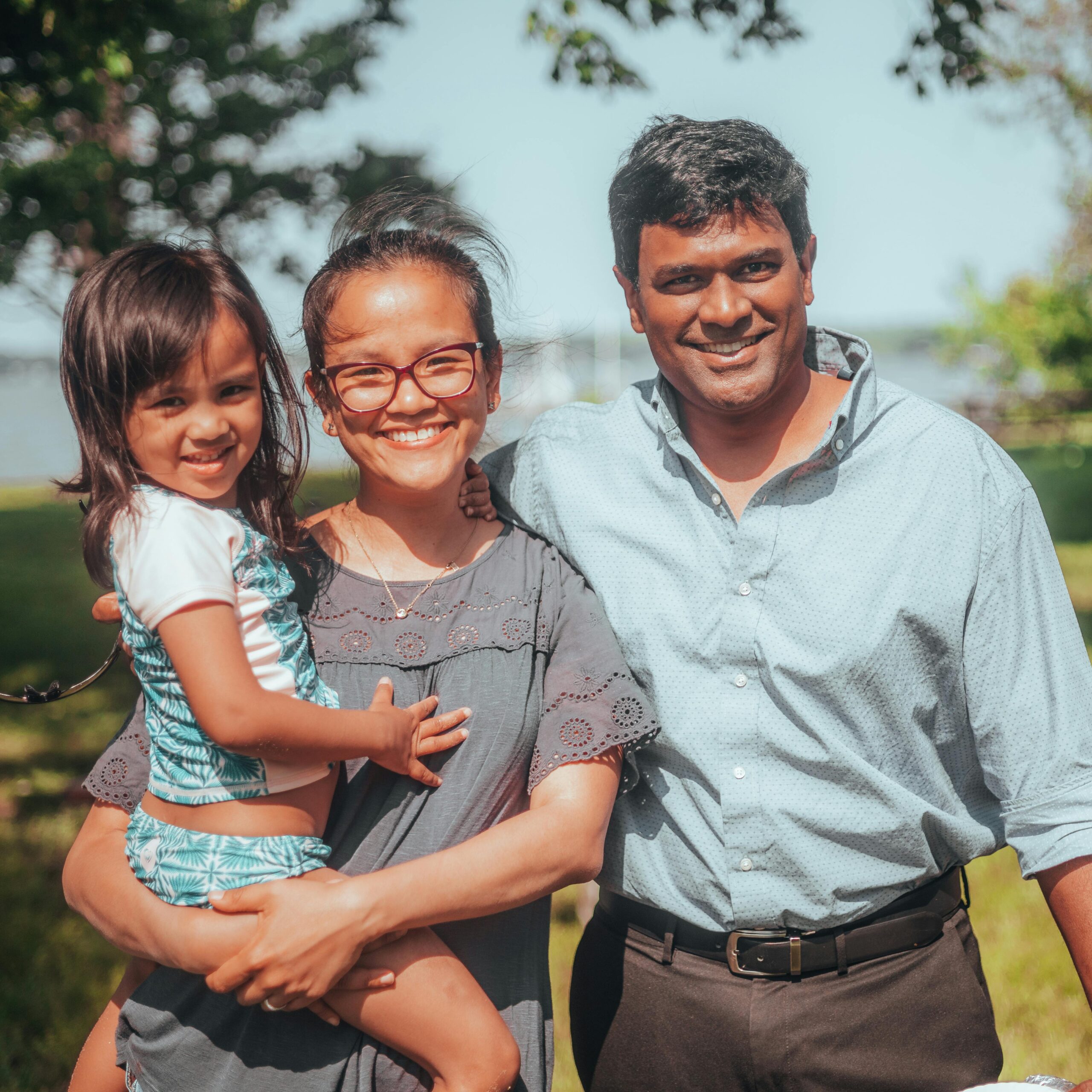 Smiling family enjoying time together outdoors in a sunny summer setting.