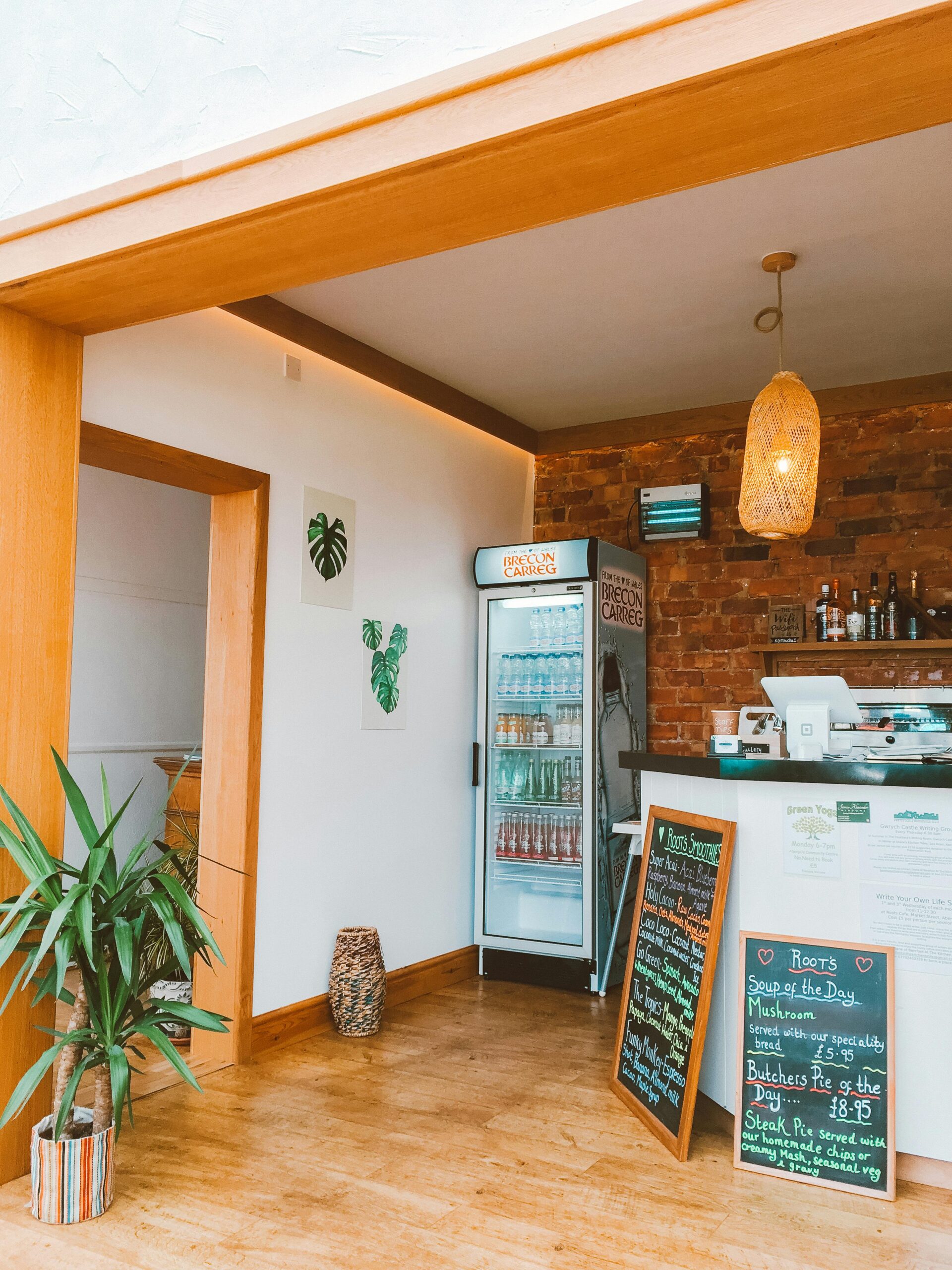 Modern café interior featuring a minimalist design with wood elements, pendant lights, and a visible menu board.